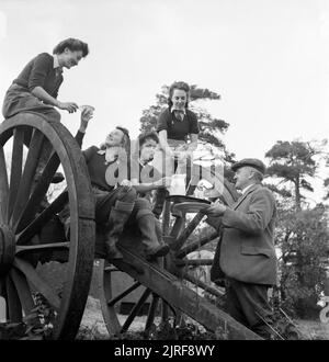 Le ragazze di terra Godetevi una calda tazza di tè dopo una dura giornata di cattura di ratto su Sussex azienda durante il 1942. Le ragazze di terra Eileen Barry, Audrey Willis, Betty lungo e Audrey Prickett Godetevi una calda tazza di tè dopo una dura giornata di cattura di ratto, come parte della loro formazione su Sussex farm. Essi sono qui seduti su grandi cartwheels, mentre l'Agricoltore Giles li porta una brocca del latte fresco da aggiungere alla loro tè. Foto Stock