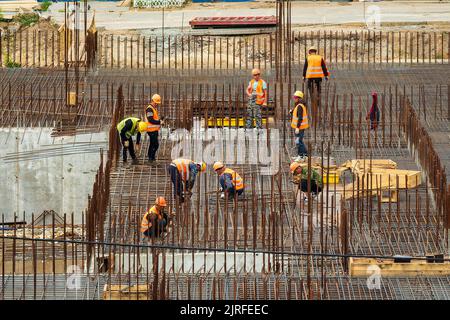 RUSSIA, KALUGA - 15 AGOSTO 2022 : Un gruppo di lavoratori che assemblano la struttura di un edificio con accessori in ferro. Foto Stock