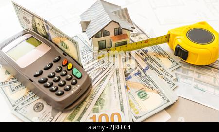 Soldi contro lo sfondo della disposizione della casa. Stipendio per i costruttori. Posti vacanti per i costruttori. Formazione nelle professioni di costruzione. Foto Stock