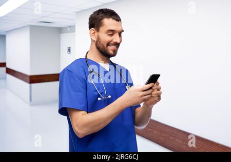 medico sorridente o infermiera maschile utilizzando lo smartphone Foto Stock