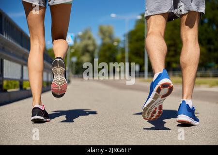 piedi di coppia sportiva che corrono lungo la strada cittadina Foto Stock