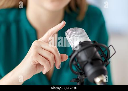 Donna con microfono podcast di registrazione in studio Foto Stock