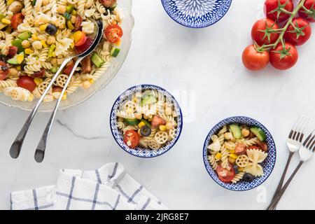 Una ciotola di insalata di pasta e due porzioni a destra. Copiare lo spazio al centro. Foto Stock