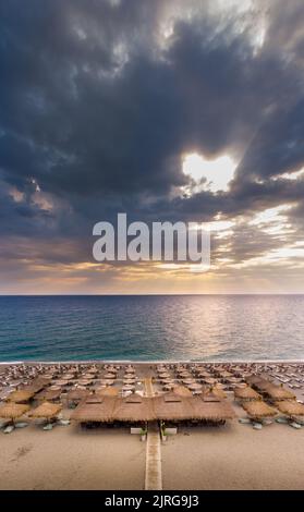 Panorama verticale paesaggio aereo o foto di mare di un bar sulla spiaggia all'alba a Agiokampos Beach, Grecia Foto Stock