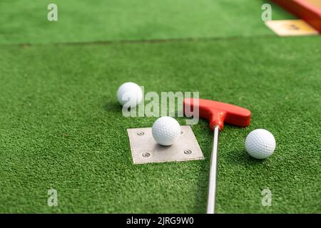 Putters e palle da golf in miniatura assortiti si inclinano su erba sintetica. Foto Stock