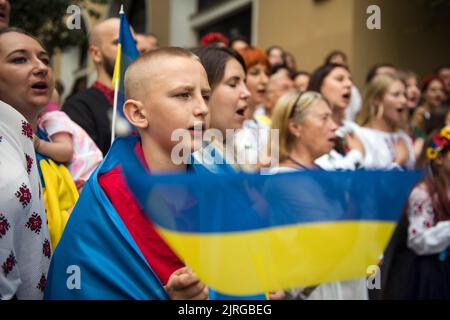 Il ragazzo ucraino sventola una bandiera durante l'evento nazionale di canto dell'inno a Varsavia. Decine di rifugiati ucraini si sono riuniti all'esterno della "Casa Ucraina" (Dom Ukrainski) a Varsavia per cantare l'inno nazionale dell'Ucraina come parte di un progetto di canto globale dell'inno. È quello di unire gli ucraini in tutto il mondo e di stabilire un record per la performance globale simultanea dell'inno. Anche gli ucraini volevano celebrare la giornata dell'indipendenza dell'Ucraina e protestare contro l'invasione russa di sei mesi iniziata il 24th febbraio. (Foto di Attila Husejnow/SOPA Images/Sipa USA) Foto Stock