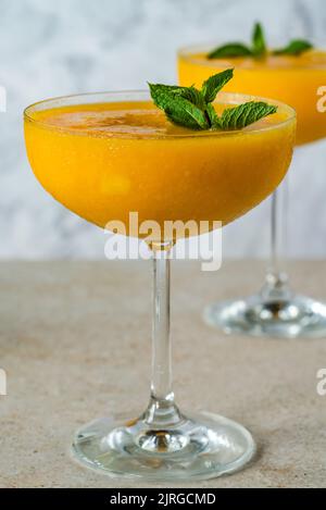 Daiquiri di mango surgelati al rum bianco guarniti con menta fresca. Foto Stock