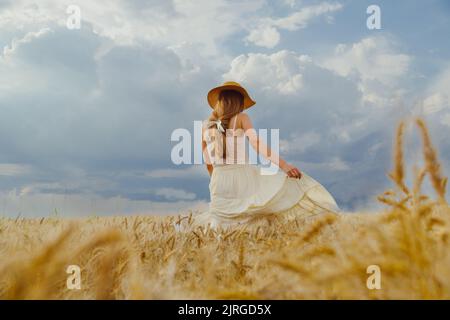 Donna in vestito rurale e cappello ballando da solo in campo di grano Foto Stock