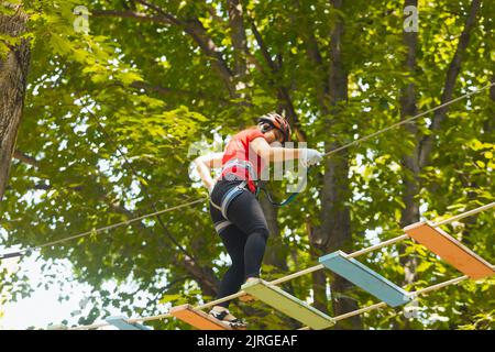 La donna sta facendo l'esercizio nel parco avventura della corda Foto Stock