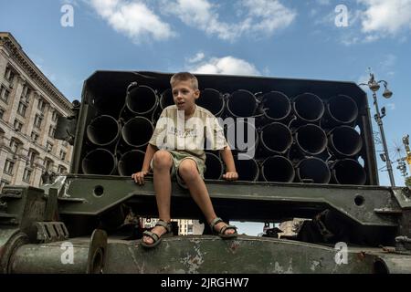 Kiev, Kiev Oblast, Ucraina. 21st ago, 2022. Un giovane ragazzo si pone per una foto con l'esposizione di un veicolo distrutto Russian Multi Rocket Launch System (MLRS) per le strade di Kyiv. Dedicato alla prossima Giornata dell'Indipendenza dell'Ucraina, e quasi 6 mesi dopo l'invasione su vasta scala dell'Ucraina il 24 febbraio, la capitale del paese Kyiv tiene una mostra sulla strada principale di Khreschaytk Street che mostra numerose attrezzature militari distrutte, Carri armati e armi dalle forze armate della Federazione Russa (AFRF). Come la piena invasione russa dell'Ucraina iniziato il 24 febbraio, la guerra tha Foto Stock