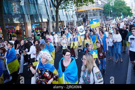 Berlino, Germania. 24th ago, 2022. I dimostranti camminano lungo Tauentzienstraße con bandiere di colori ucraini e colombe di pace. La marcia di protesta dell'associazione 'Vitsche' si svolge oggi in occasione della Giornata dell'Indipendenza dell'Ucraina. Credit: Annette Riedl/dpa/Alamy Live News Foto Stock