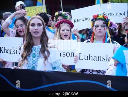 Berlino, Germania. 24th ago, 2022. Le donne dipinte di rosso tengono cartelli con le città ucraine mentre dimostrano alla marcia di protesta dell'associazione 'Vitsche' per la Giornata dell'Indipendenza dell'Ucraina e contro la guerra. Credit: Annette Riedl/dpa/Alamy Live News Foto Stock