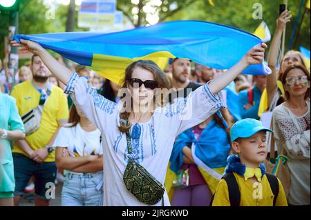 Berlino, Germania. 24th ago, 2022. Un dimostratore tiene una bandiera in colori ucraini in aria durante la marcia di protesta dell'associazione 'Vitsche' per la Giornata dell'Indipendenza dell'Ucraina e contro la guerra. Credit: Annette Riedl/dpa/Alamy Live News Foto Stock