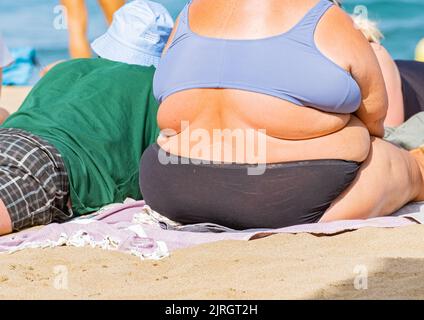 Donna obesa che prende il sole sulla spiaggia in Spagna Foto Stock