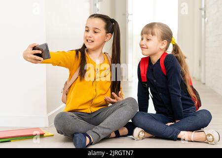 Due compagni di scuola moderni che giocano nello smartphone durante la pausa tra le lezioni Foto Stock