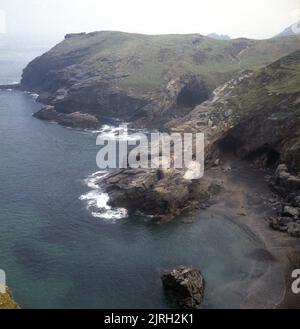 1971, vista dall'alto, dalle rovine del castello di Tintagel, della costa frastagliata della Cornovaglia settentrionale, Inghilterra, Regno Unito. Il sito del castello di Tintagel è storicamente associato alle leggende di Re Artù, menzionato per la prima volta nella mitologica 'Historia Regum Britanniae' da Geoffrey di Monmouth. Foto Stock