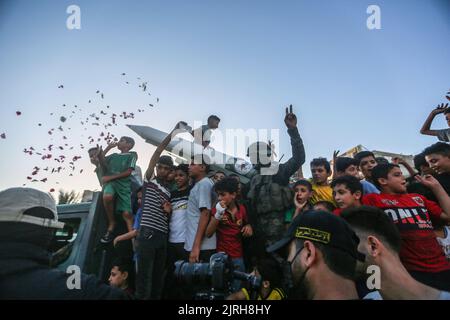 Rafah, territori palestinesi. 24th ago, 2022. Un combattente palestinese del movimento islamico della Jihad è in piedi con la gente mentre partecipa a un raduno anti-Israele a Rafah. Credit: Mohammed Talatene/dpa/Alamy Live News Foto Stock