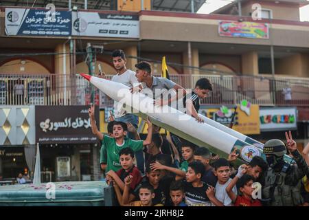 Rafah, territori palestinesi. 24th ago, 2022. Un combattente palestinese del movimento islamico della Jihad è in piedi con la gente mentre partecipa a un raduno anti-Israele a Rafah. Credit: Mohammed Talatene/dpa/Alamy Live News Foto Stock