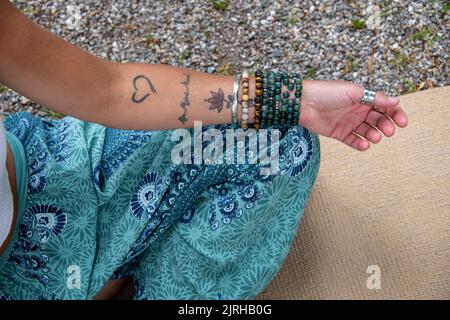 Braccio e mano di una donna europea con tatuaggi e gioielli Foto Stock