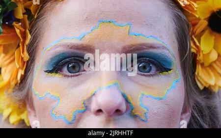 Berlino, Germania. 24th ago, 2022. Un dimostratore ha dipinto il profilo del paese sul suo volto per la marcia di protesta dell'associazione 'Vitsche' nella Giornata dell'Indipendenza dell'Ucraina. Credit: Annette Riedl/dpa/Alamy Live News Foto Stock