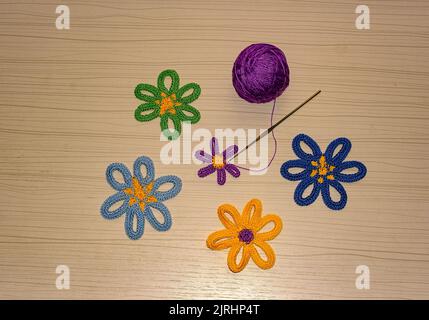 Fiori coccolati e pallina di filo viola su fondo di legno. Foto Stock