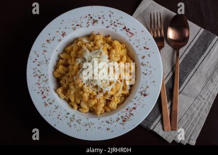 Mac e formaggio, pasta di maccheroni all'americana con salsa di formaggio su un tavolo rustico scuro, vista dall'alto Foto Stock