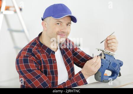 l'uomo cambia lama su un seghetto alternativo elettrico Foto Stock