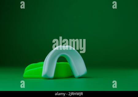 due protezioni in gomma per bocca, bianche e verdi, protezione per labbra e denti, concept Foto Stock