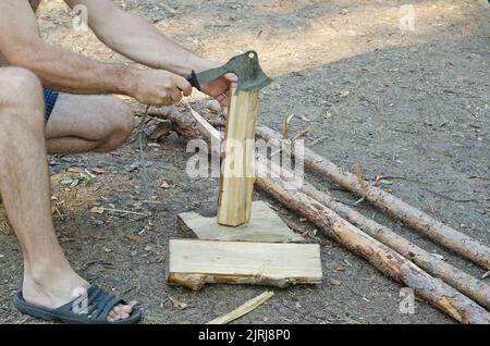 un uomo trita legno con un'ascia per il riscaldamento. Foto Stock