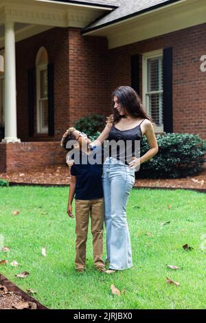 Una grande sorella e un fratellino fuori casa si guardano l'un l'altro Foto Stock