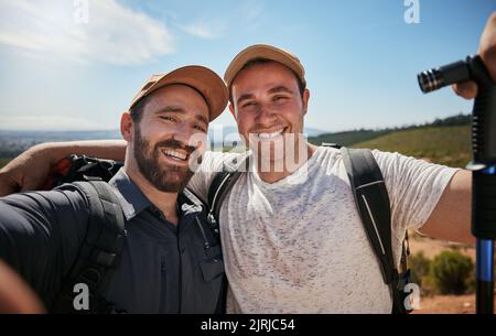 Amici, fratelli o escursionisti che prendono un selfie mentre camminano all'aperto nella natura condividendo l'esperienza sui social media. Gli uomini attivi, in forma e atletici prendono Foto Stock