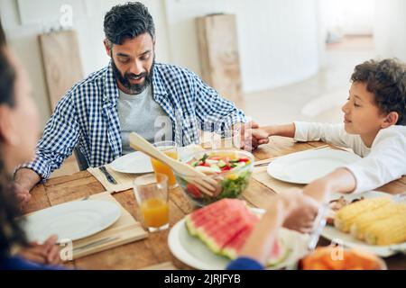 Ringraziate sempre per le vostre benedizioni: Una famiglia che prega insieme prima di gustare un pasto al tavolo. Foto Stock