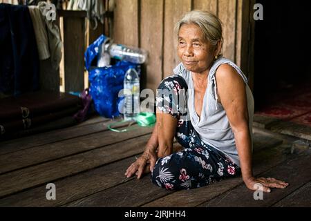 Una sola vecchia donna indigena seduta nella sua casa su pavimento in legno Foto Stock