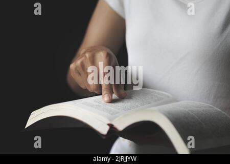 Leggere con una mano che indica le Scritture. Donna fedele e cristiana che prega idee, credenze, fede, preghiere, desideri. Foto Stock