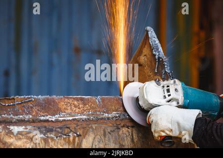 Mola elettrica su struttura in acciaio in fabbrica scintille da mola. Sgrossatura e lucidatura metalli, scintille in lavorazione metalli. Foto Stock