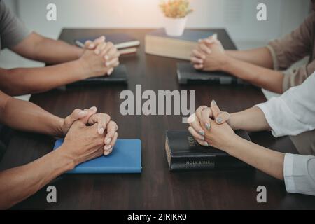 Concetto cristiano mettere le mani sulla Bibbia e pregare Dio. Studia la Bibbia insieme. Vivere la vita. Pregare insieme. Combinare il potere della speranza o l Foto Stock