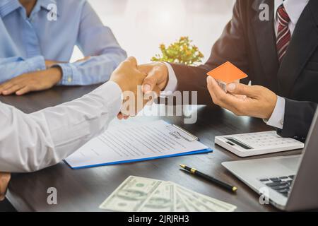 Agenti immobiliari che scuotono le mani per congratularsi con i compratori dopo aver dato un contratto di acquisto, un'idea di contratto. Case di commercio e immobili. Foto Stock