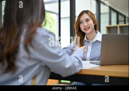 Donna d'affari asiatica attraente e amichevole o manager femminile intervistando una donna candidato in ufficio. Concetto di colloquio di lavoro Foto Stock