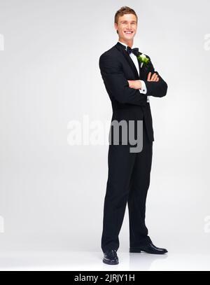 Matrimonio, matrimonio e sposo con un bel uomo in piedi braccia incrociate in studio su uno sfondo bianco. Maschio felice in un vestito o tuxedo con un Foto Stock