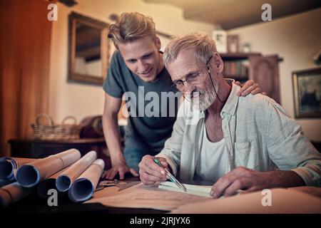 Due menti sono migliori di una: Un padre e suo figlio che lavorano su un disegno per la loro attività di famiglia a casa. Foto Stock