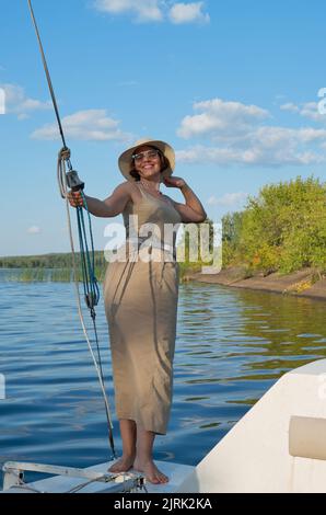 Ragazza sulla prua di una nave a vela contro il cielo blu Foto Stock