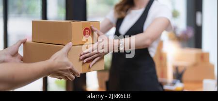 cliente che riceve un pacco di scatole di cartone dall'addetto alla consegna al mattino, concetto di servizio di consegna. Foto Stock