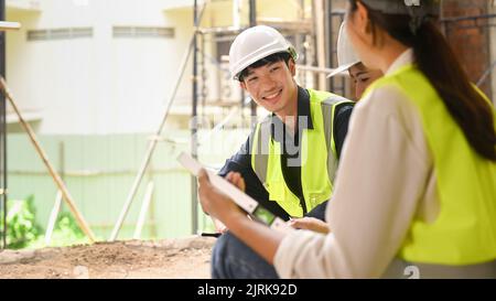 Uomo ingegnere supervisore e architetto indossare caschi di sicurezza discutere il processo di costruzione insieme mentre si visita un nuovo edificio Foto Stock