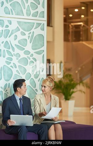 Colleghi che analizzano grafici e grafici finanziari durante la riunione Foto Stock