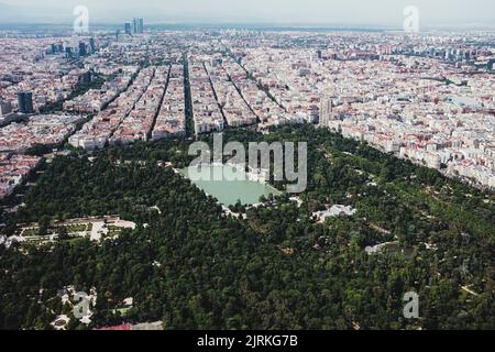 Dall'alto drone vista panoramica della città con densa infrastruttura con lago e parco a El Retiro a Madrid, Spagna Foto Stock
