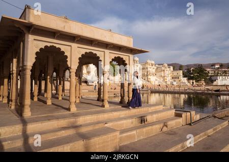 Corpo pieno donna asiatica guardando lontano mentre si trova sotto il tetto di edificio ad arco sulla costa del Lago Sacro Pushkar in Rajasthan, India Foto Stock