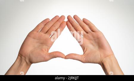 le palme di una donna sono piegate in un triangolo su uno sfondo bianco. Foto di alta qualità Foto Stock