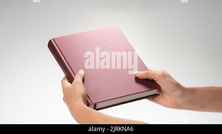 Le mani delle donne che tengono un libro chiuso, effetto sotto una lampada di notte. Foto di alta qualità Foto Stock