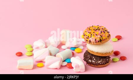 Dolci - torta, dolci, draghe, marshmallow su sfondo rosa Foto Stock