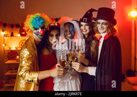 Ritratto di allegri amici adulti felici con bicchieri di champagne a casa festa per Halloween. Foto Stock